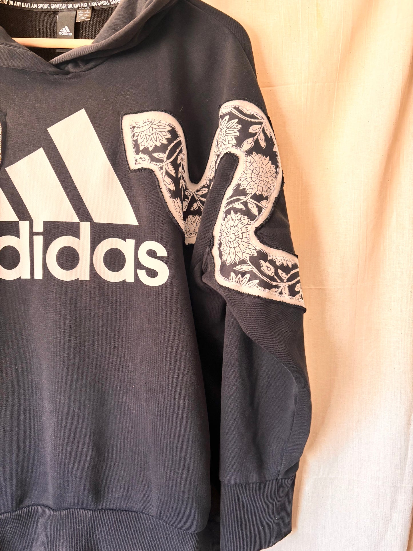 Black Adidas hoodie with floral designs on sleeves