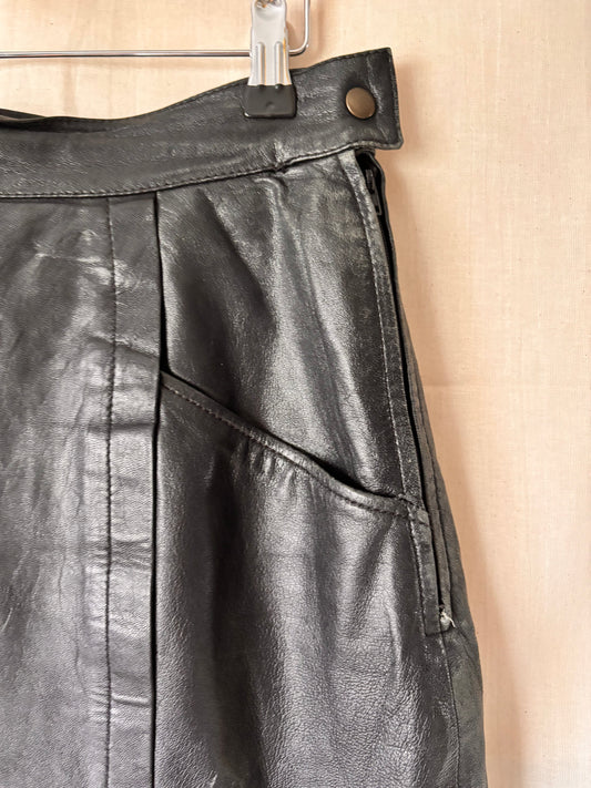 close up view of pocket detail of Black leather skirt on a beige background