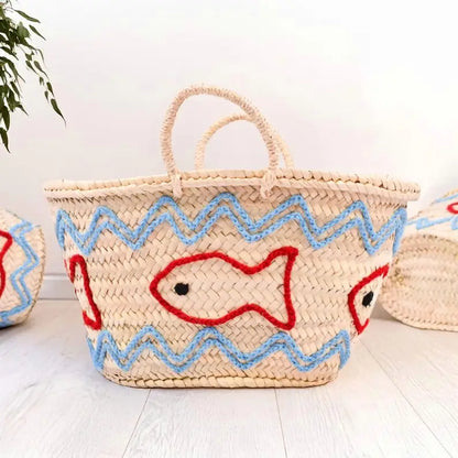 Woven basket with fish design on a light wooden surface