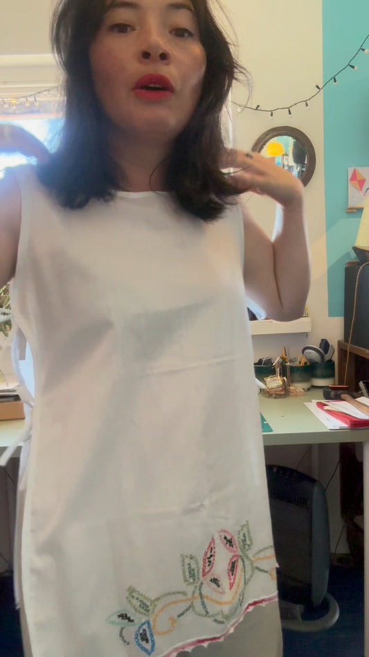 Woman wearing a white tunic with embroidery in a casual indoor setting