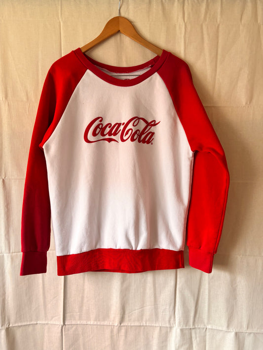 Red and white sweatshirt with Coca-Cola logo on a beige background