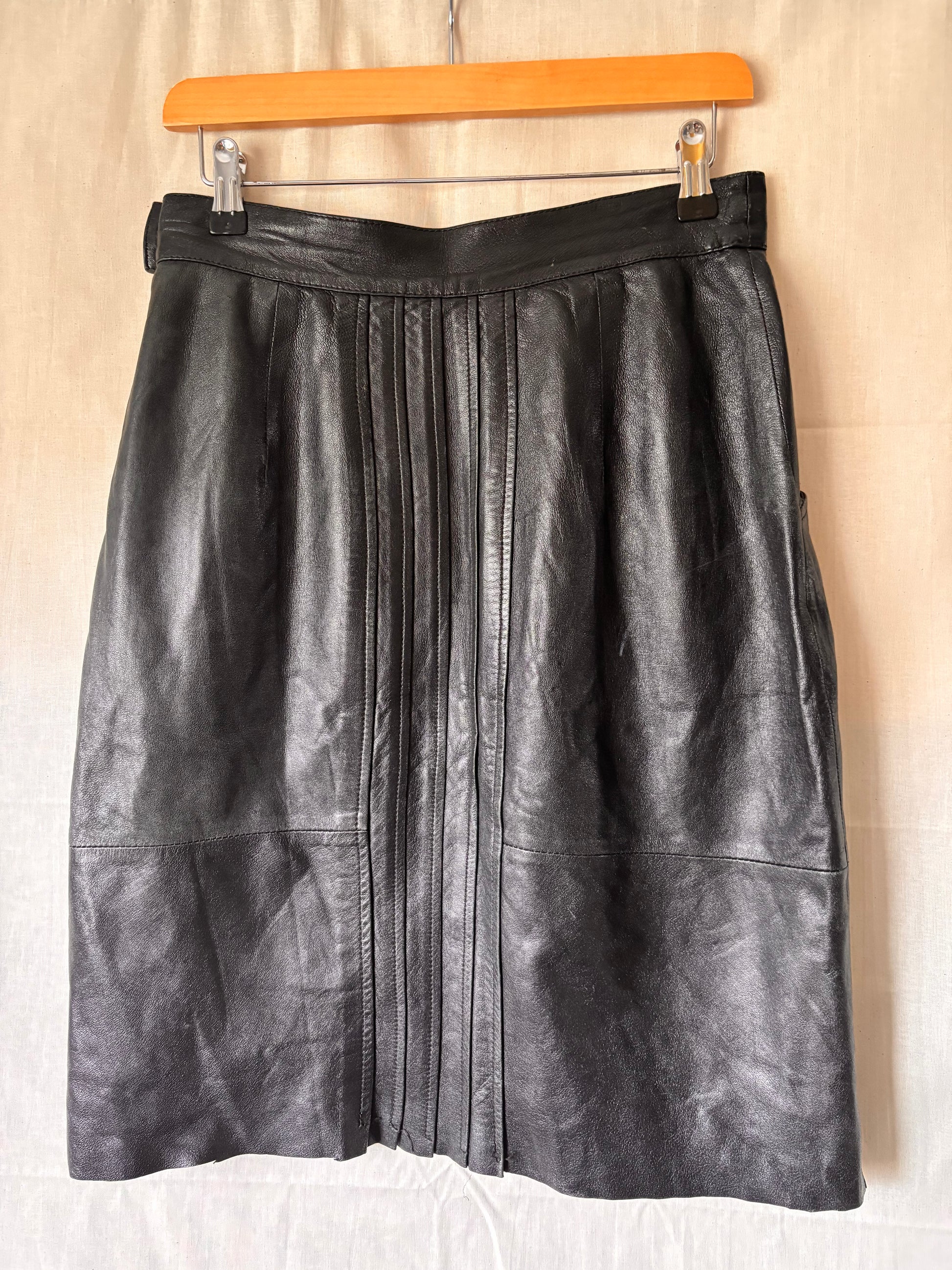 back view of black leather skirt showing pleating detail going down the centre of skirt