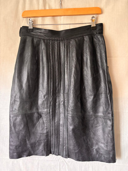 back view of black leather skirt showing pleating detail going down the centre of skirt
