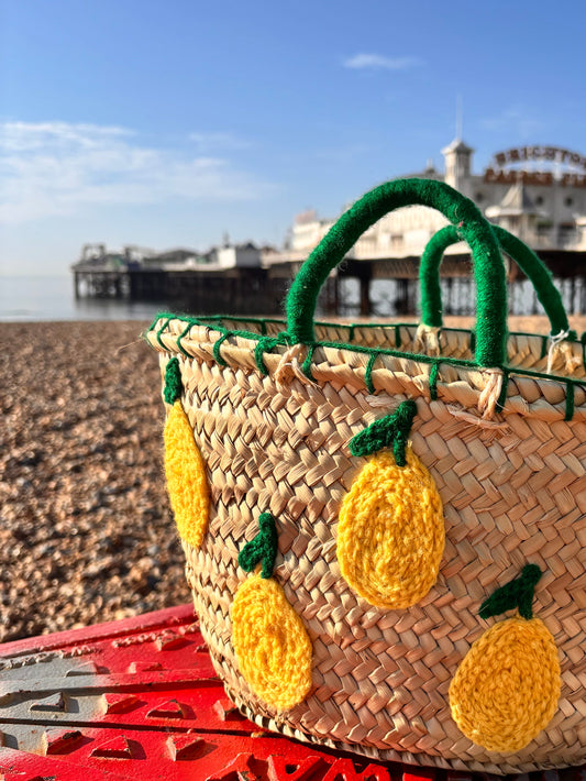 Woven bag with lemon embroidered design. Photographed on Brighton beach in front of Brighton Palace Pier. 