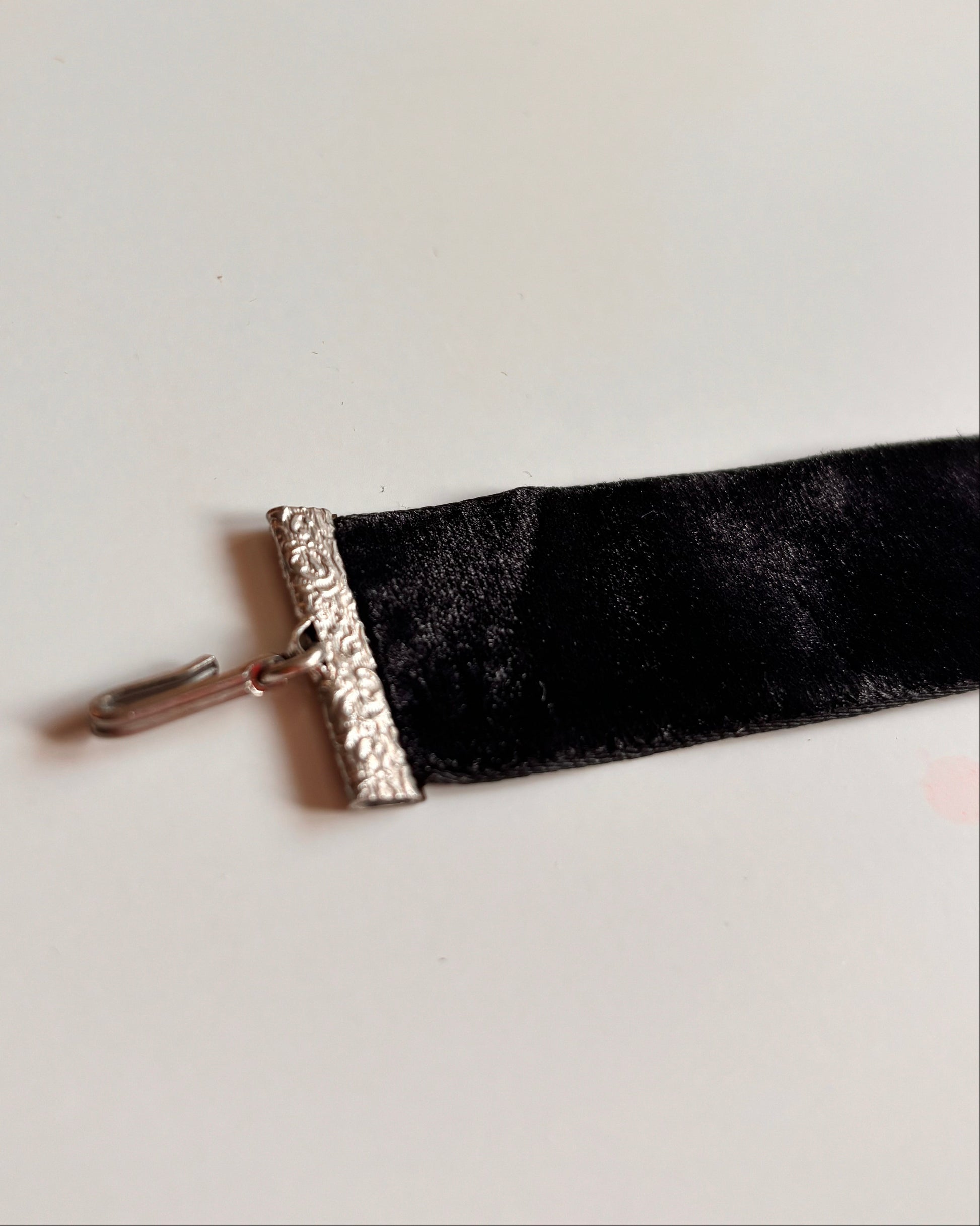 Black velvet ribbon choker with silver trim on a white background