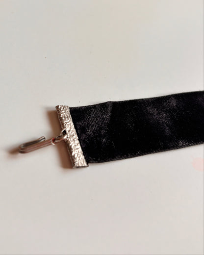 Black velvet ribbon choker with silver trim on a white background