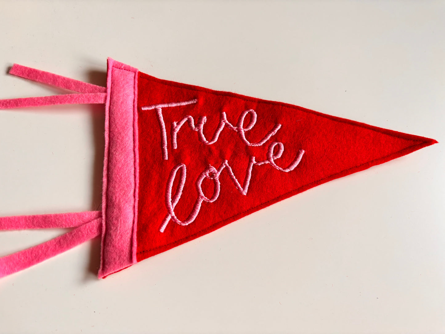 Red felt pennant with 'True Love' embroidery on a light background