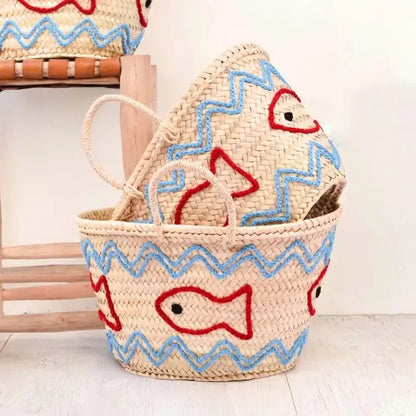 Woven basket with fish designs on a light wooden floor