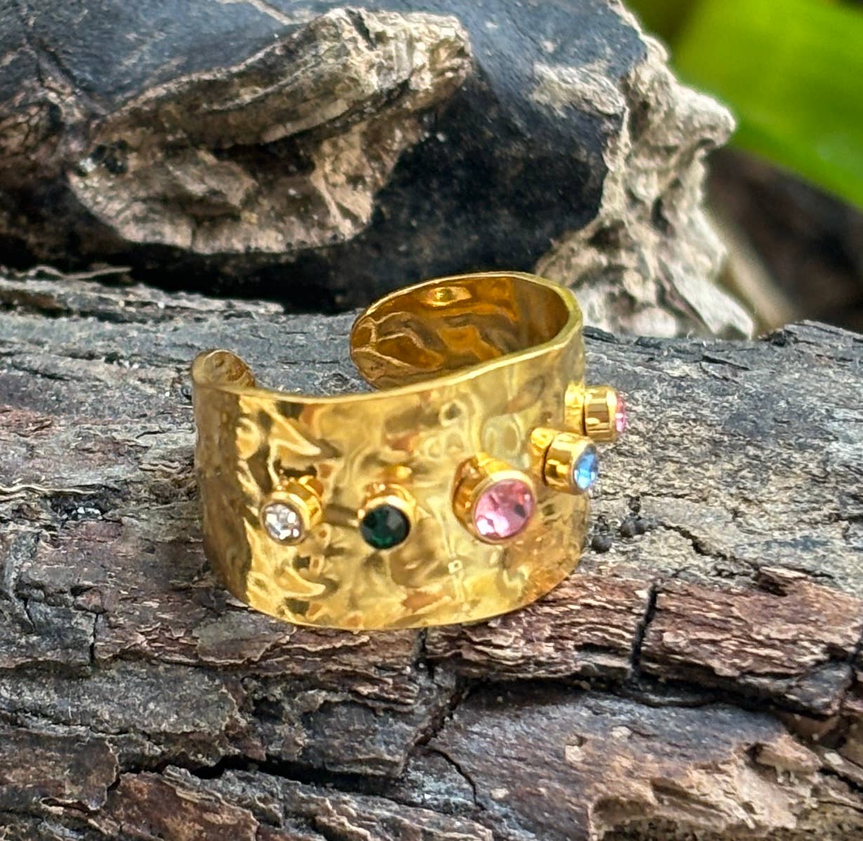 18ct Gold-plated hammered chunky wide ring with colourful gemstones on a wooden surface